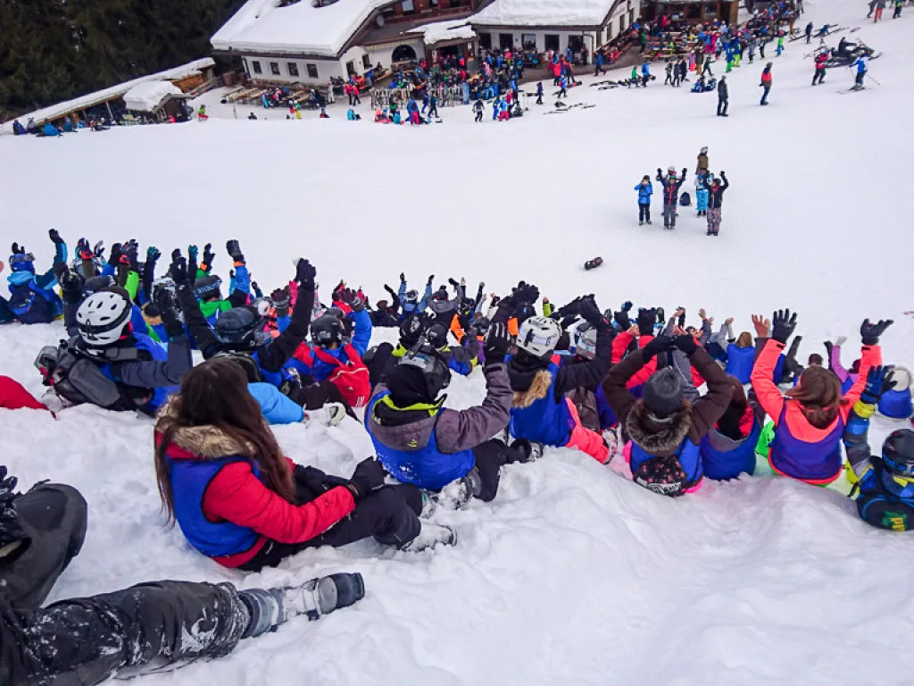 Gruppe liegt jubelnd im Schnee vor der Hütte.